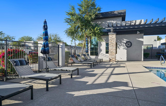 A poolside area with sun loungers and a shade structure.