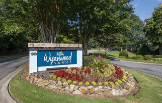 a sign for Wynnwood Vinings apartments on a roundabout with a flower garden