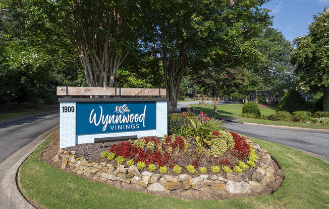 a sign for Wynnwood Vinings apartments on a roundabout with a flower garden