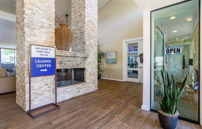 A leasing center sign is displayed in a spacious room with a stone fireplace.