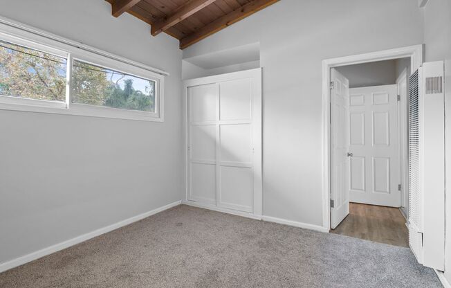 an empty bedroom with a closet and a window