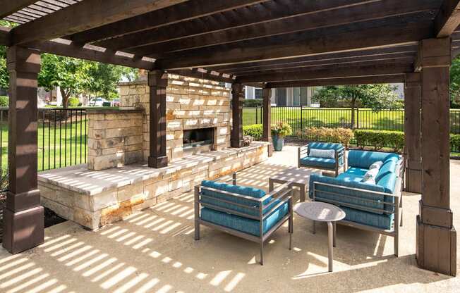 a covered patio with a stone fireplace and blue couches