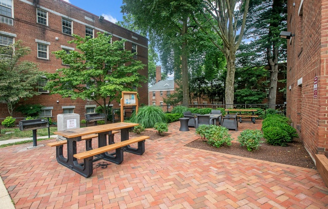 a brick patio with a picnic table and benches in front of a brick building