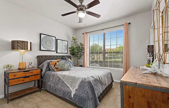 a bedroom with a large window and a ceiling fan