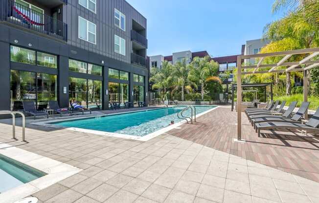 a swimming pool with lounge chairs in front of a building