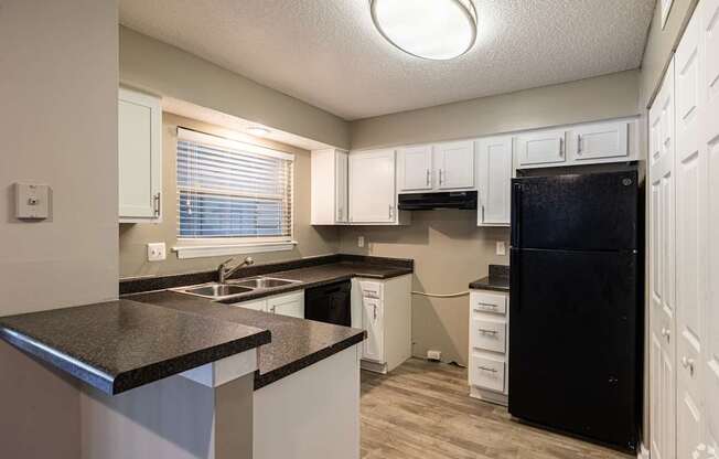 A kitchen with black countertops and white cabinets.