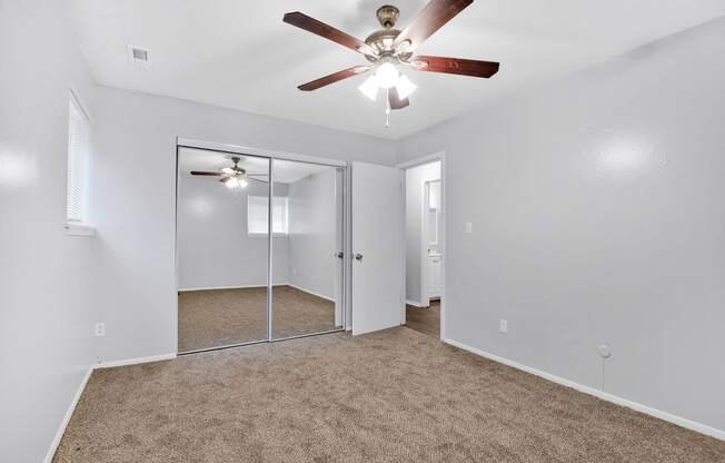 carpeted room with ceiling fan and large closet