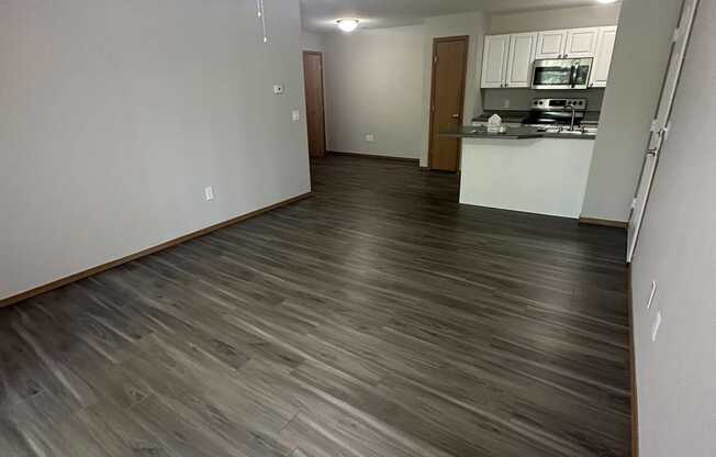 a living room and kitchen with wood flooring and a ceiling fan