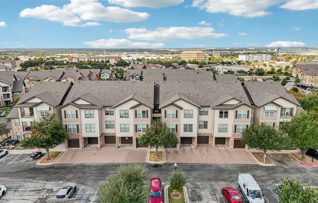 A large apartment complex with a parking lot in front.