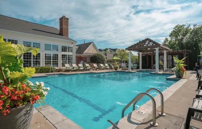 A large swimming pool with a diving board and a building in the background.