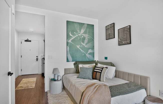 A bedroom with a bed, nightstand, and two wall art pieces at The Indie in Allston.