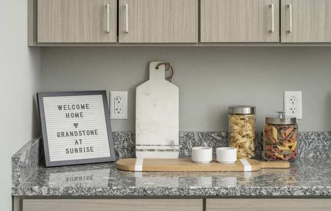 a kitchen counter with a sign that reads welcome home and gratitude at sunset at Grandstone at Sunrise, Peoria, AZ