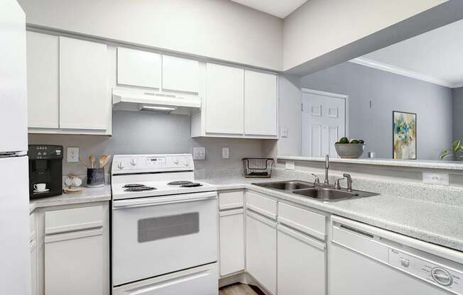 A white kitchen with a stove, sink, and refrigerator.