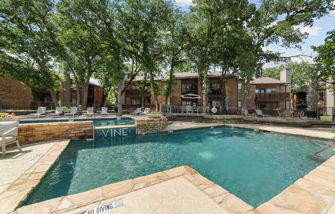 A pool surrounded by trees and a stone wall with the word Vine on it.