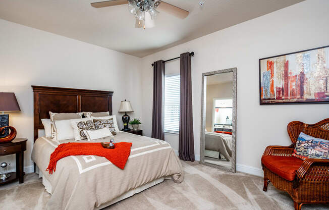 Furnished master bedroom with ceiling fan, carpet flooring, and window at Riverstone apartments for rent in Macon, GA