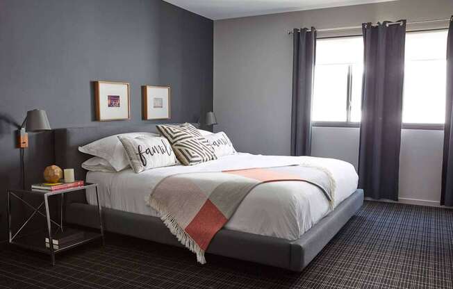 A bedroom with a large bed and a window with curtains.