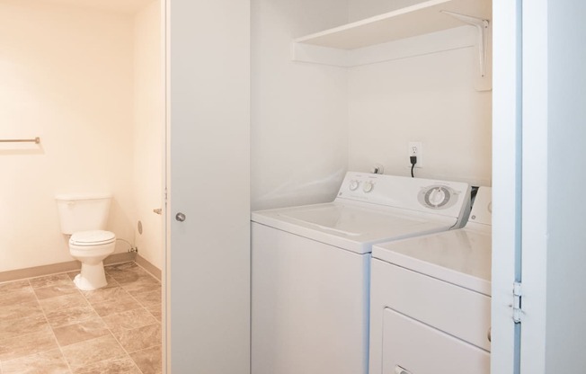 a bathroom with a washer and dryer and a toilet