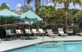 a swimming pool with chaise lounge chairs and umbrellas