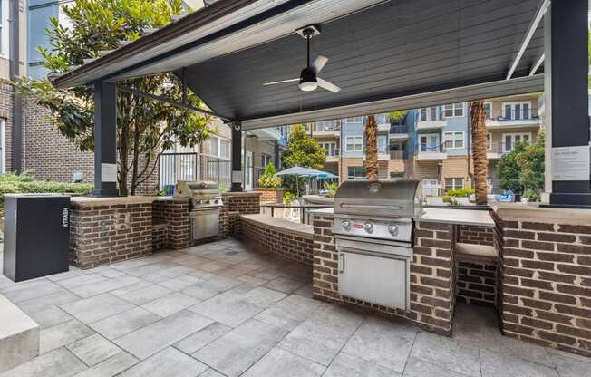 an outdoor kitchen with a grill and a ceiling fan