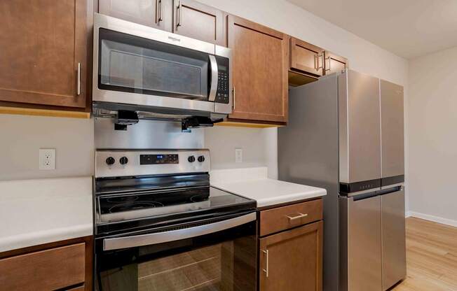 A kitchen with a stainless steel refrigerator and a black oven.