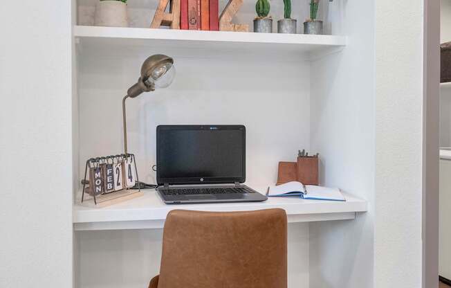 A brown chair is in front of a desk with a laptop on it.