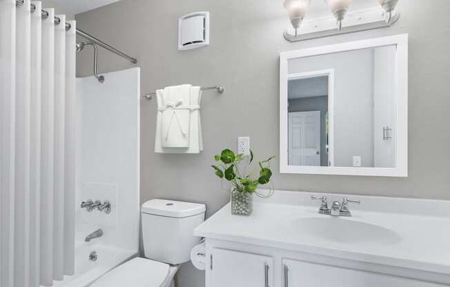 a white bathroom with a mirror and a toilet and a sink