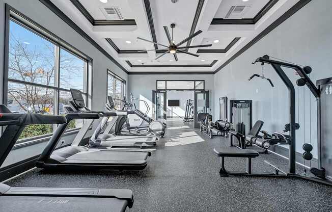 A spacious gym with treadmills, elliptical machines, and a ceiling fan.