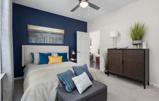 A bedroom with a bed, a dresser, and a ceiling fan.