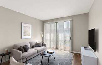 A living room with a grey couch, a black chair, a small table, a television, and a window with blinds.