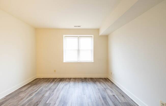 an empty room with white walls and wood floors  at Charlesgate Apartments, Towson
