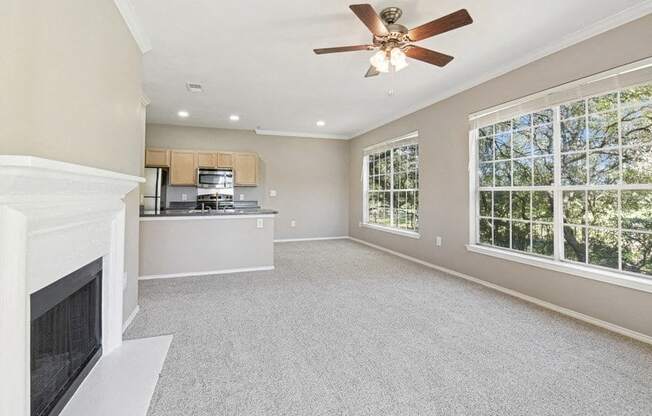 an empty living room with a fireplace and a ceiling fan