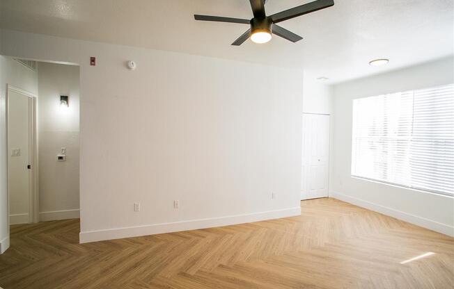 an empty living room with a ceiling fan