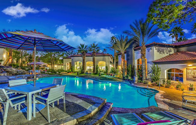 A poolside area with a table and chairs under an umbrella.