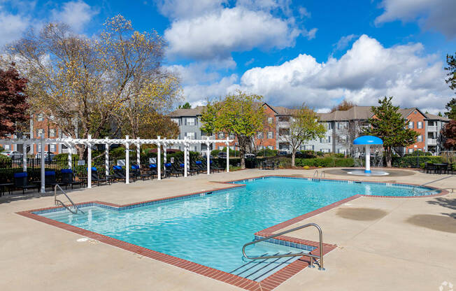 A large swimming pool surrounded by a white fence and trees.