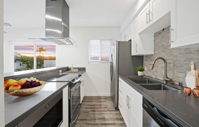 a kitchen with stainless steel appliances and a bowl of fruit on the counter