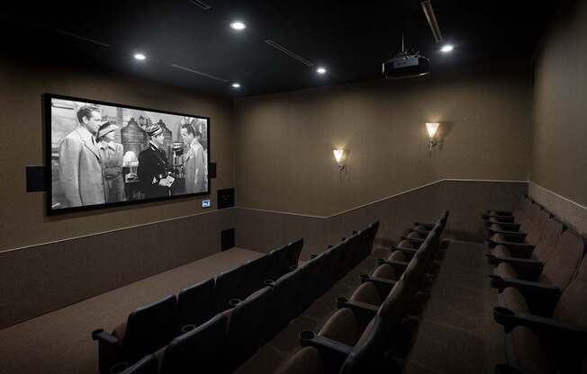 A black and white photo is displayed on a wall above a row of seats in a dark room.