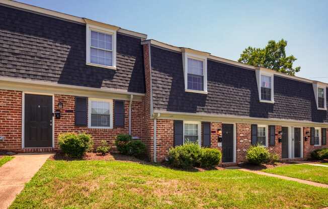 a brick apartment building with a sidewalk in front of it