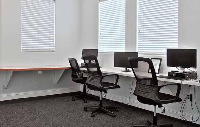 an office with three desks with chairs and a computer