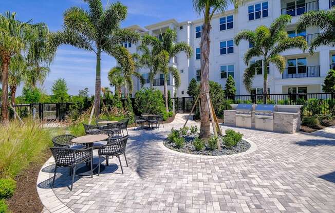 a patio with tables and chairs and palm trees at Altis Grand Lake Willis, Orlando, FL