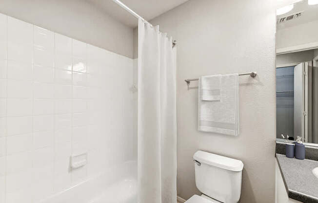 Model Bathroom with White Cabinets, Wood-Style Flooring & Shower/Tub at Lake Cameron Apartments located in Apex, NC.