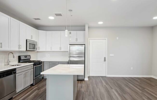a kitchen with white cabinets and stainless steel appliances at Metro 303, Hempstead New York