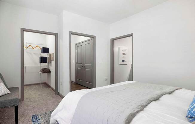 A bedroom with a large bed and a grey armchair.