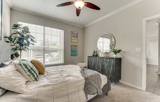 A bedroom with a bed, a dresser, and a ceiling fan.
