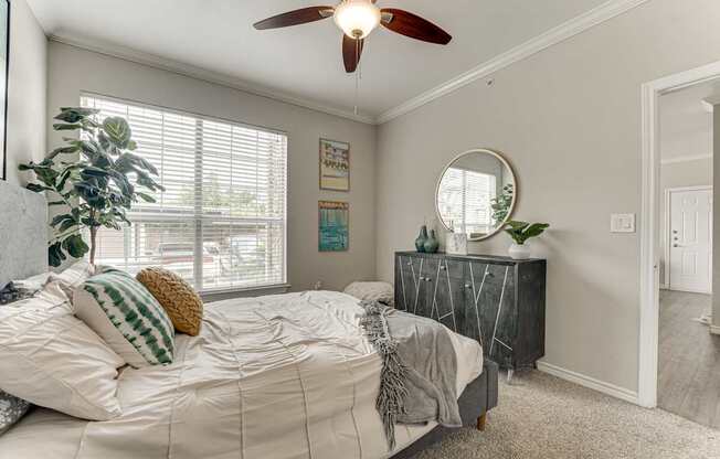 A bedroom with a bed, a dresser, and a ceiling fan.