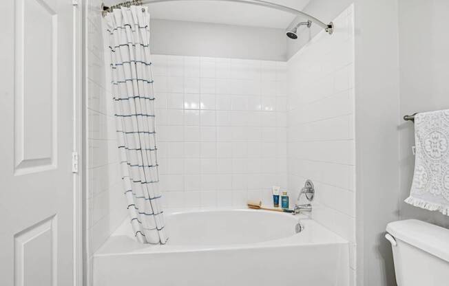 A white bathroom with a white tub and a white shower curtain.