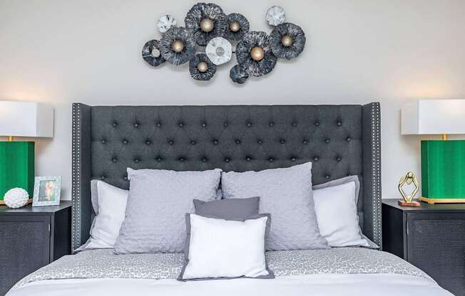 A bed with a black headboard and grey pillows is in the image.