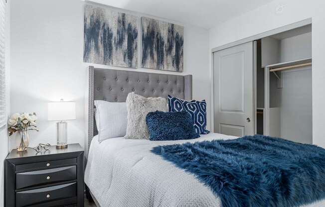 A bedroom with a bed, nightstand, and a painting on the wall.