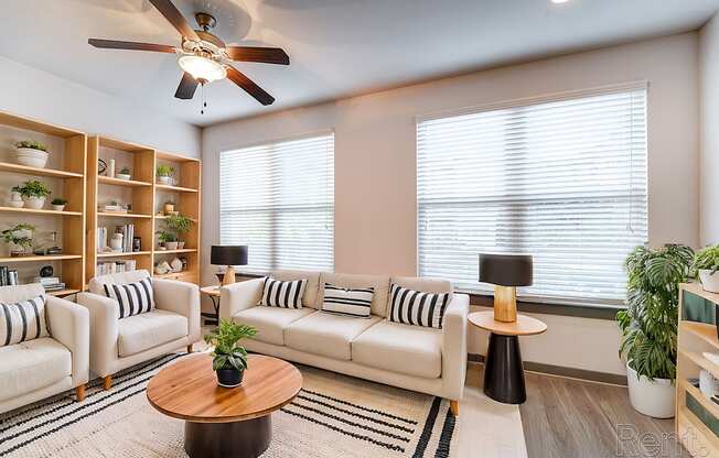 A living room with a white sofa, a wooden coffee table, and a ceiling fan.