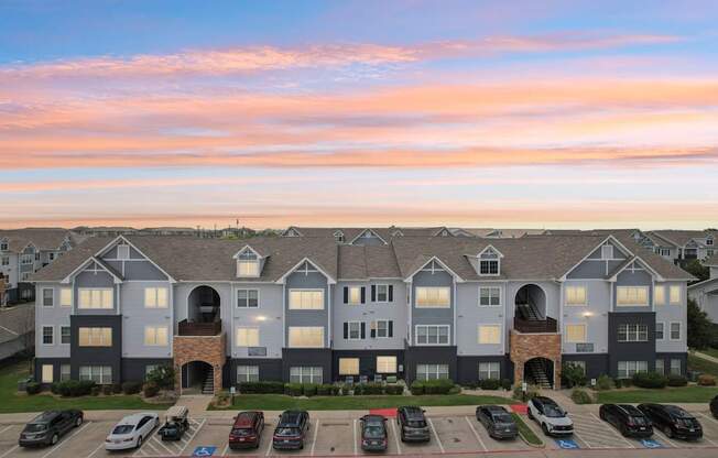 A large apartment complex with a parking lot in front.