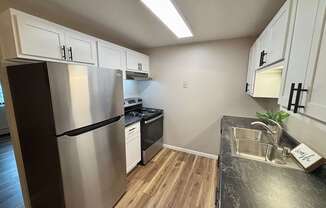 A kitchen with a black counter top and stainless steel appliances.